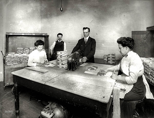 Staff uses machine to cut banknotes in half.