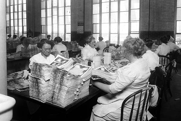 Staff inspecting and counting banknotes.
