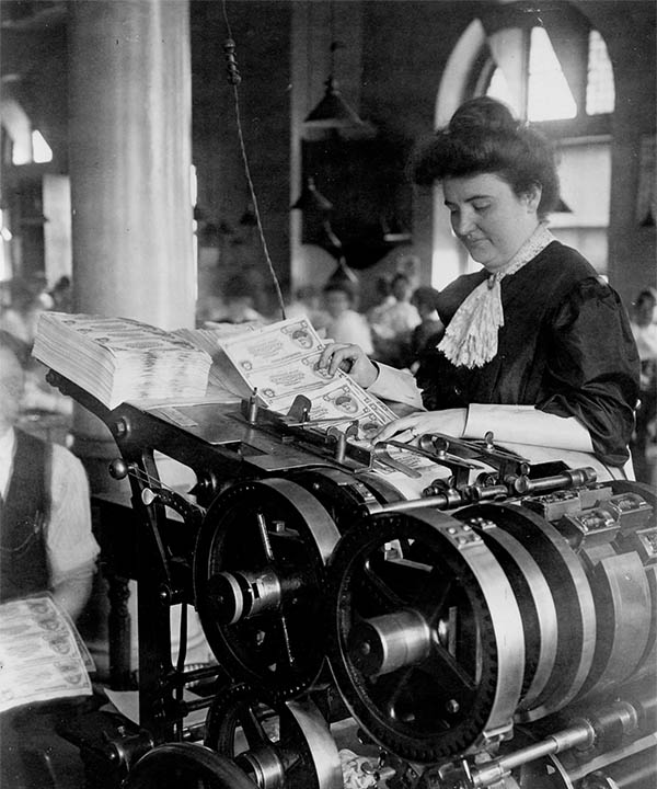 Employee numbering national banknotes with rotary numbering press.